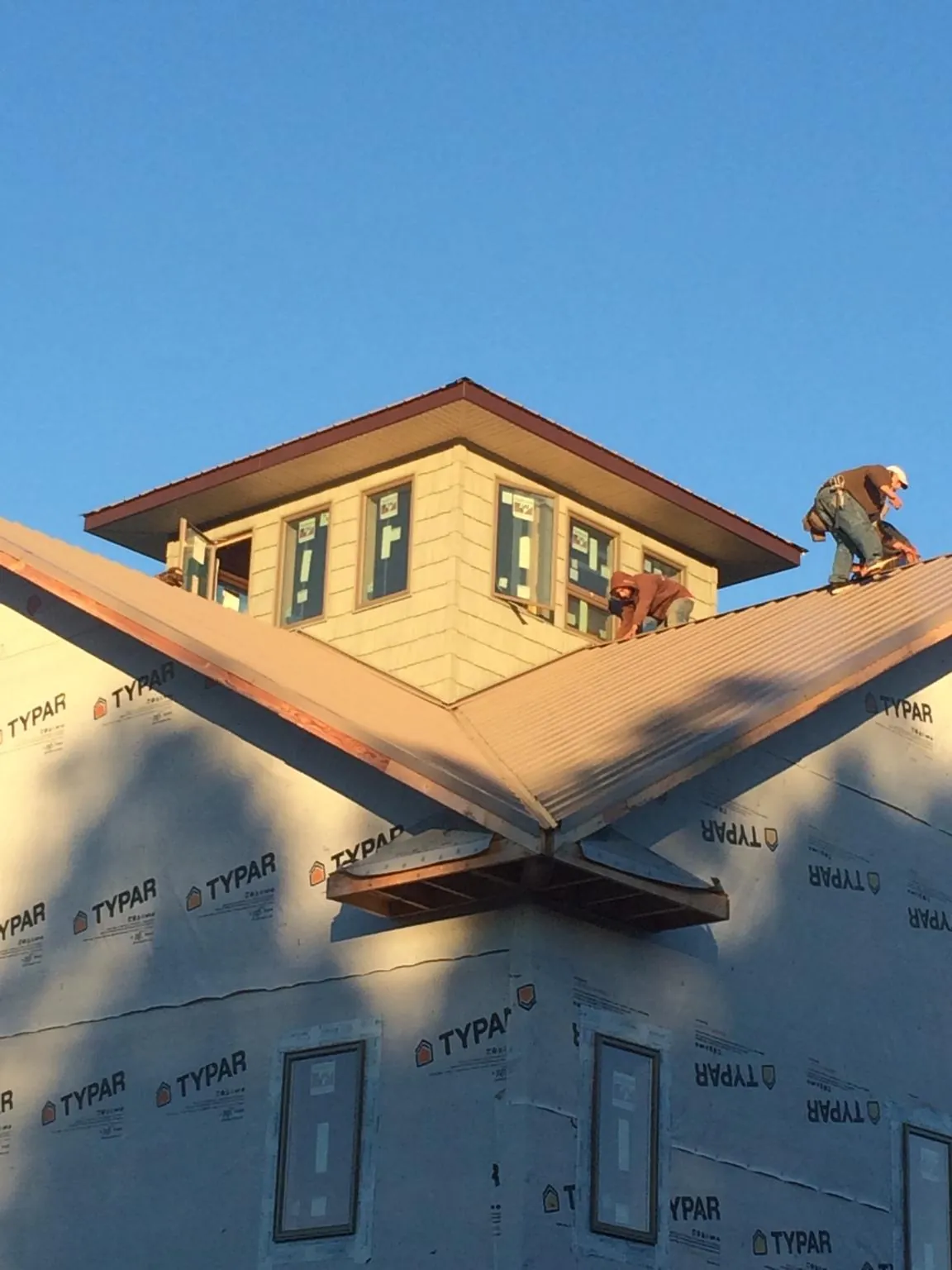 Roofers working around a rooftop cupola on a new metal roof at sunset — Roof Waterproofing in Westfield by Roofing Brothers